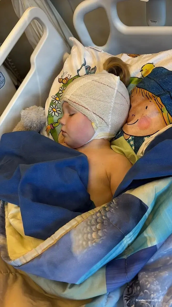 Guusje slaapt met een verband om haar hoofd, kort na een operatie.